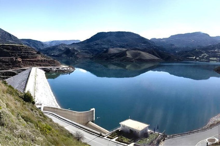 A dam with a reservoir, mountains in the background, and a clear sky. 3