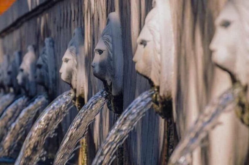A row of sculpted heads with flowing water. 5