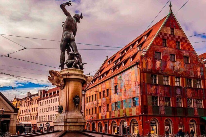 A statue on a pedestal in a square with buildings in the background. 1