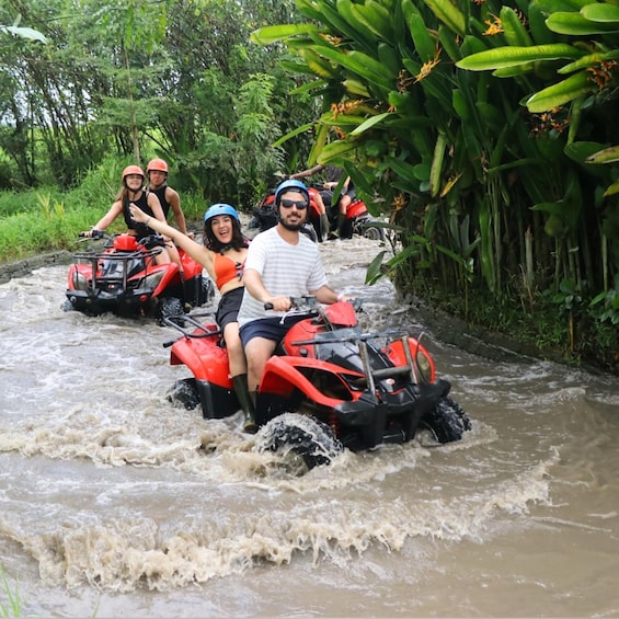 People riding red ATV's on a muddy river. 5