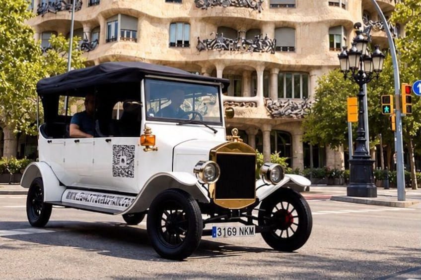 Un'auto d'epoca parcheggiata di fronte a un edificio con balconi e lampioni decorativi. 1