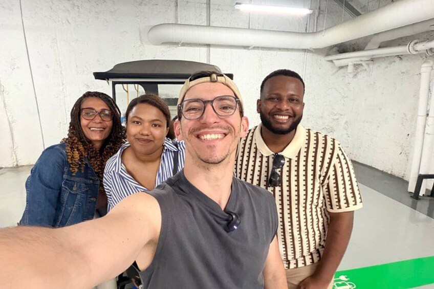 Un gruppo di persone in un interno, con una parete bianca e un tappeto verde sullo sfondo. 5