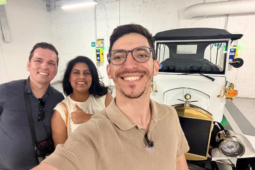 Un'auto d'epoca, una persona che si fa un selfie e un muro bianco con una porta. 4