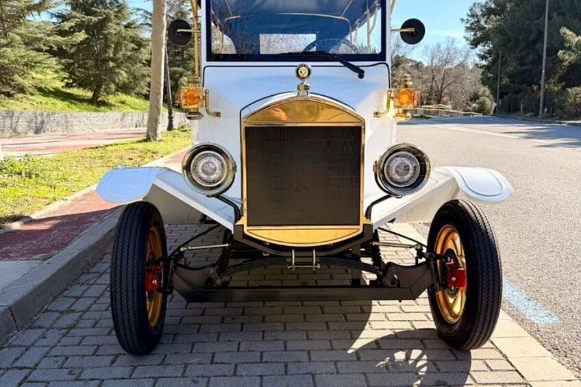 Un'auto d'epoca parcheggiata su una superficie pavimentata, con uno sfondo di erba e alberi. 2