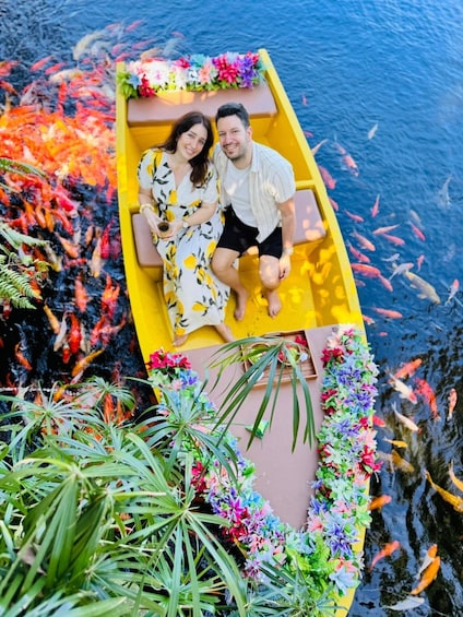 A couple in a yellow boat surrounded by colorful koi fish and greenery. 5
