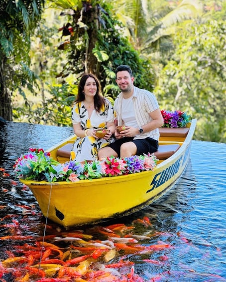 A couple in a yellow boat decorated with colorful flowers, surrounded by water and greenery. 1