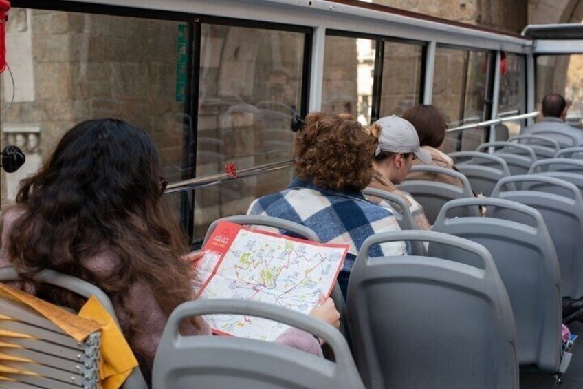 A bus interior with passengers seated and reading maps. 5