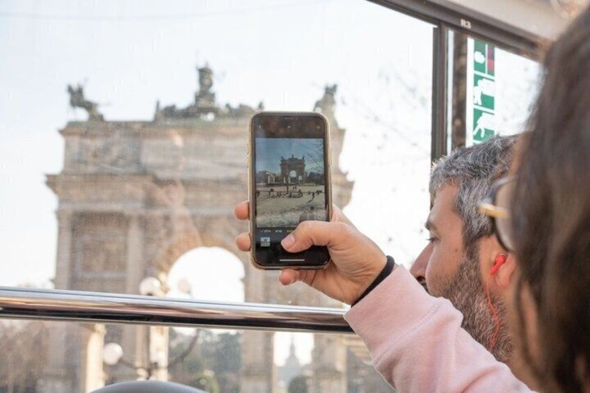 A person taking a photo of a historic archway with a smartphone. 1