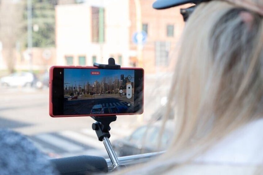 A smartphone on a tripod capturing a street scene with buildings and a clear sky. 4