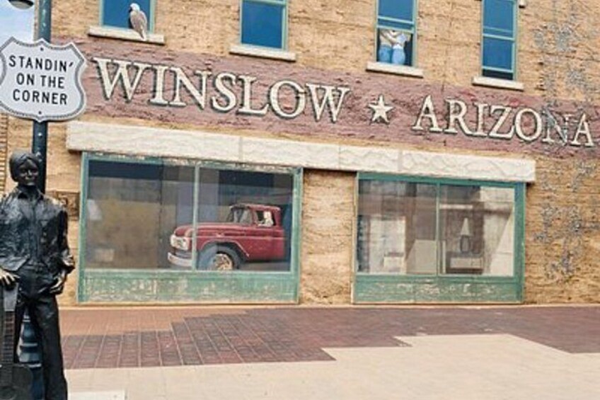 Ein Gebäude mit einem Schild, auf dem 'WINSLOW ARIZONA' steht, und ein Oldtimer ist durch das Fenster zu sehen. 3