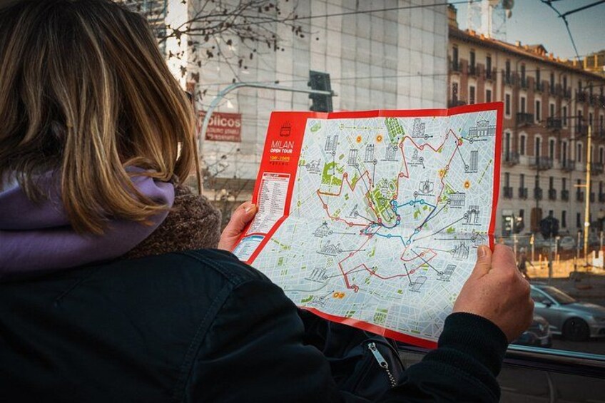 A person holding a red map of Milan. 5