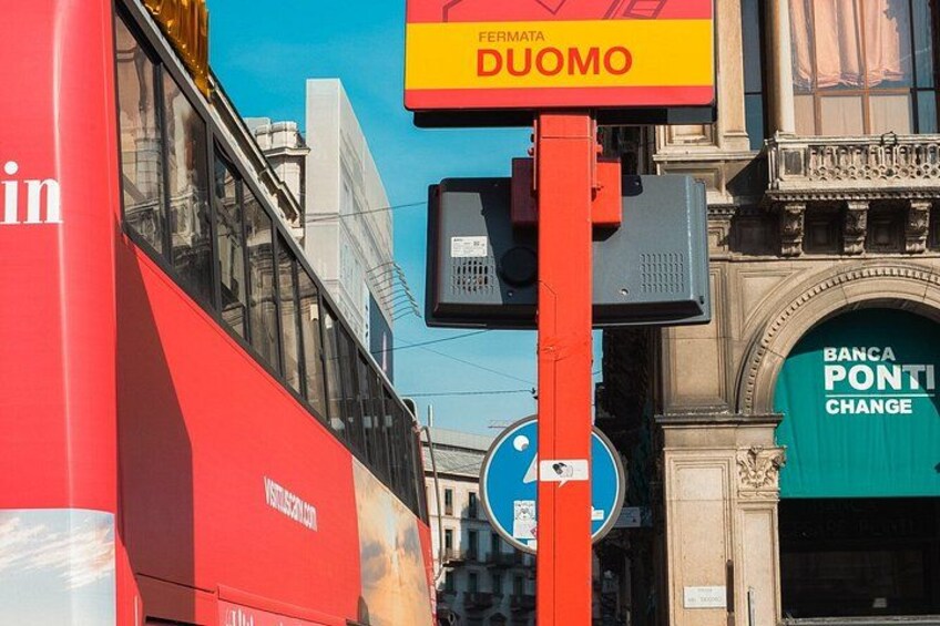 A red bus, a traffic sign, and a building with a green sign. 2
