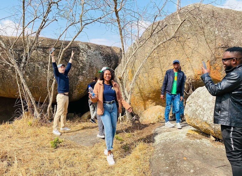 A group of people hiking on a rocky trail with large boulders and sparse vegetation. 4