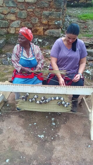 Two individuals engaged in weaving with a traditional loom. 2