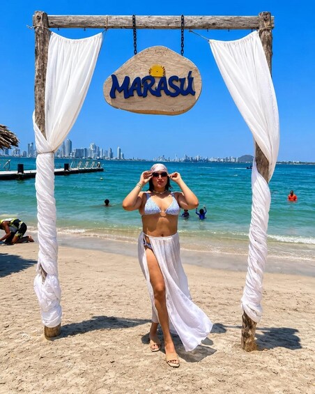 A beach scene with a wooden archway labeled 'MARASU' and a city skyline in the background. 1
