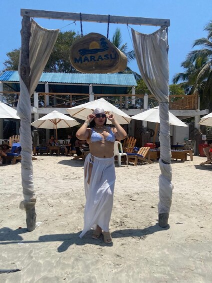 A beach scene with a sign reading 'MARASU' and a woman adjusting her hat. 3