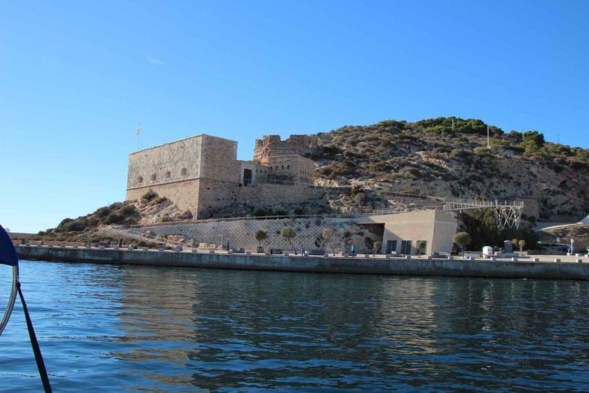 A historic stone fortress on a hill by a calm body of water. 2