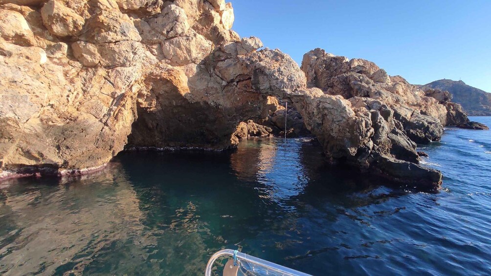 A rocky coastline with clear water and a boat in the foreground. 4