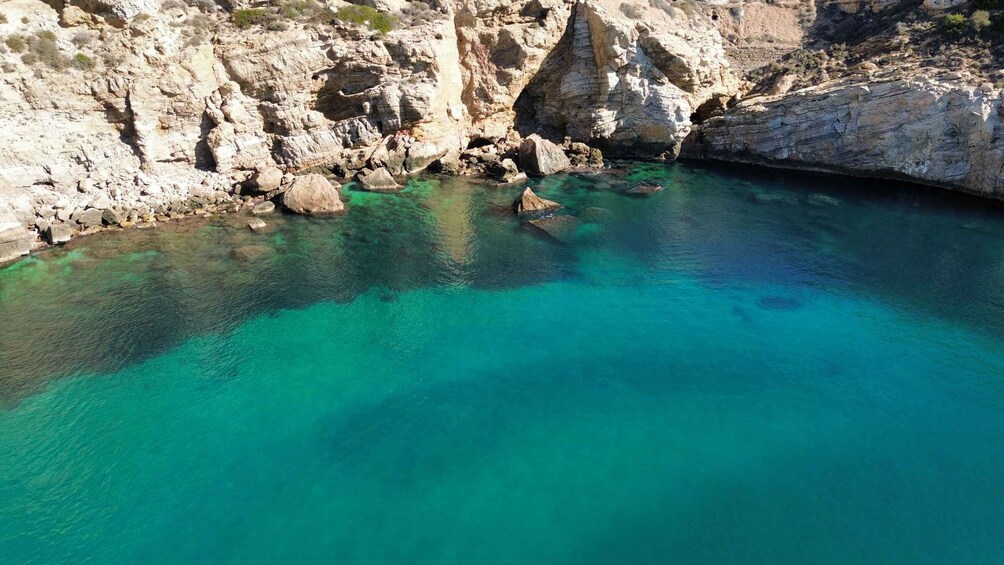 A coastal landscape with clear turquoise waters, rocky cliffs, and a narrow passage between the rocks. 5