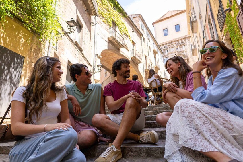 A group of people sitting on steps in a narrow street with buildings on either side. 5