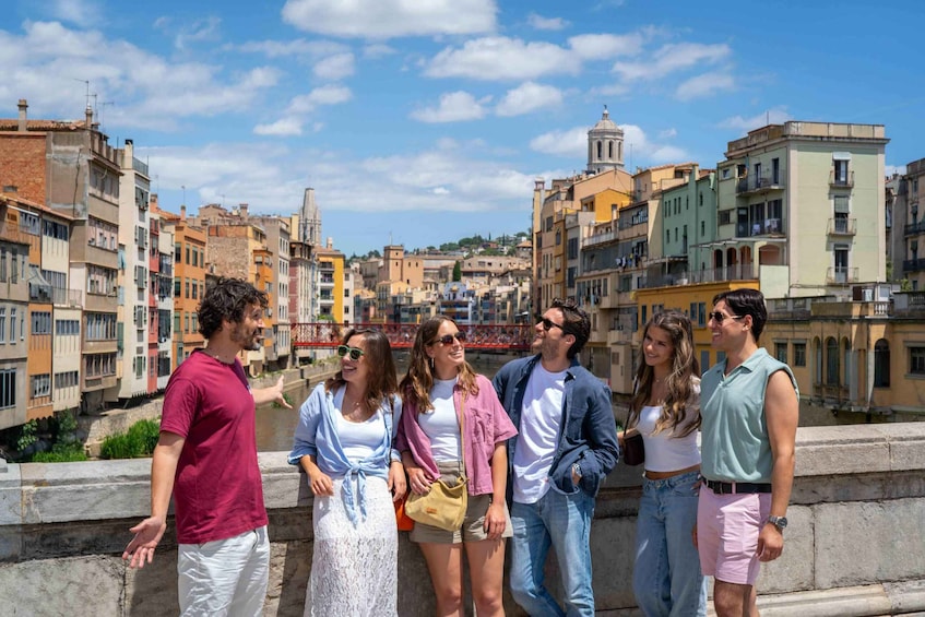 A group of people standing on a bridge with a cityscape in the background. 2