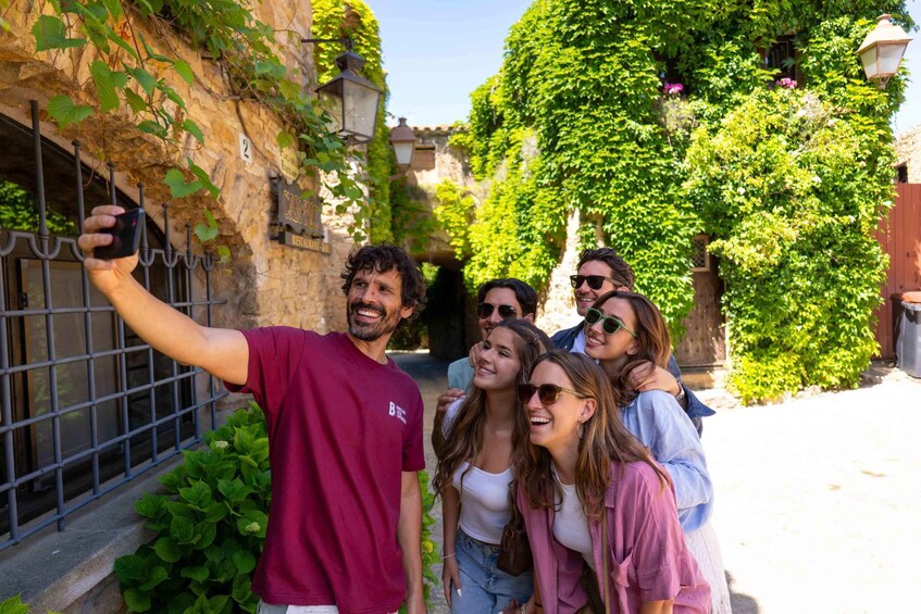 A group of people taking a selfie in a narrow alley with stone walls and greenery. 4