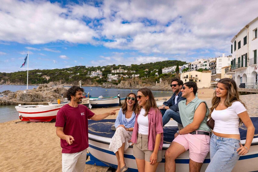 A group of people on a boat at a beach with buildings and hills in the background. 1