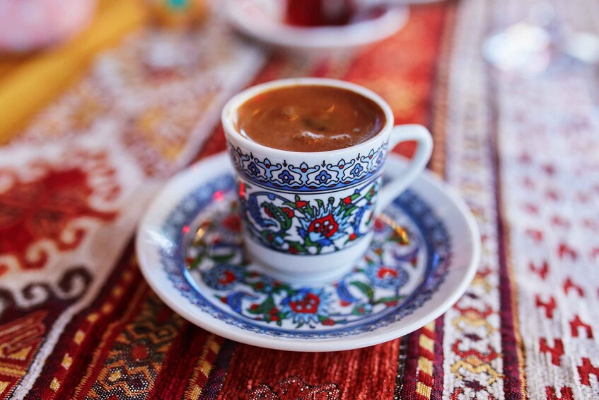 A cup of coffee on a patterned tablecloth. 2