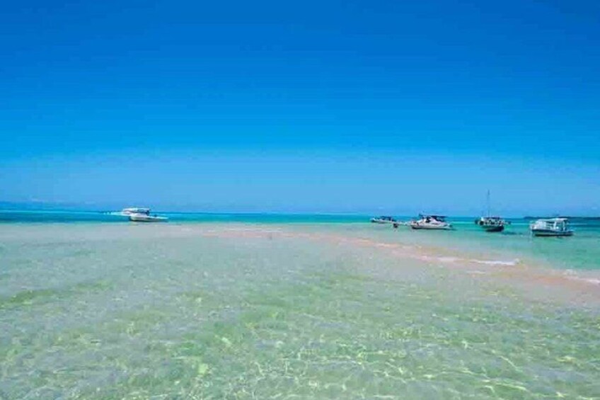Un mar azul y transparente con barcos fondeados en aguas poco profundas. 5