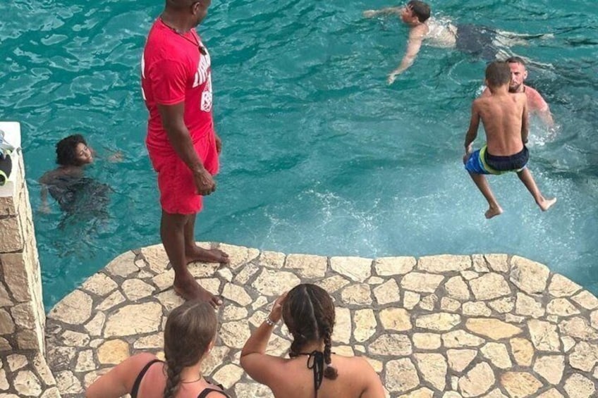 A swimming pool with people in the water and on the edge. 2