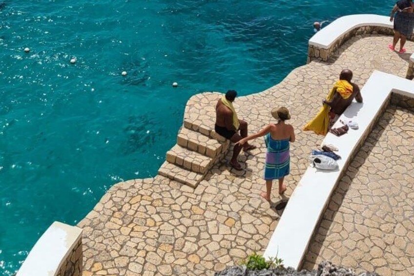 Une piscine en pierre, avec des personnes qui se détendent au bord. 4