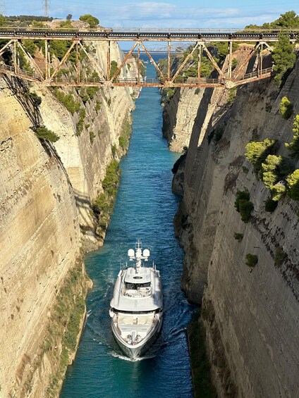 A narrow waterway flanked by steep cliffs, with a bridge overhead and a boat navigating the channel. 5