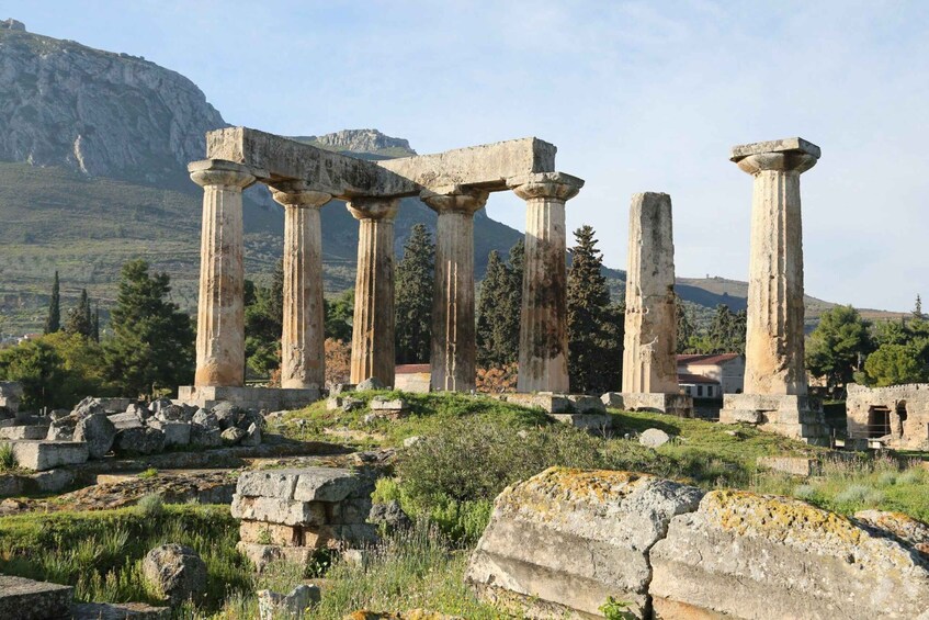 Ancient ruins with columns, a mountain, and trees in the background. 2