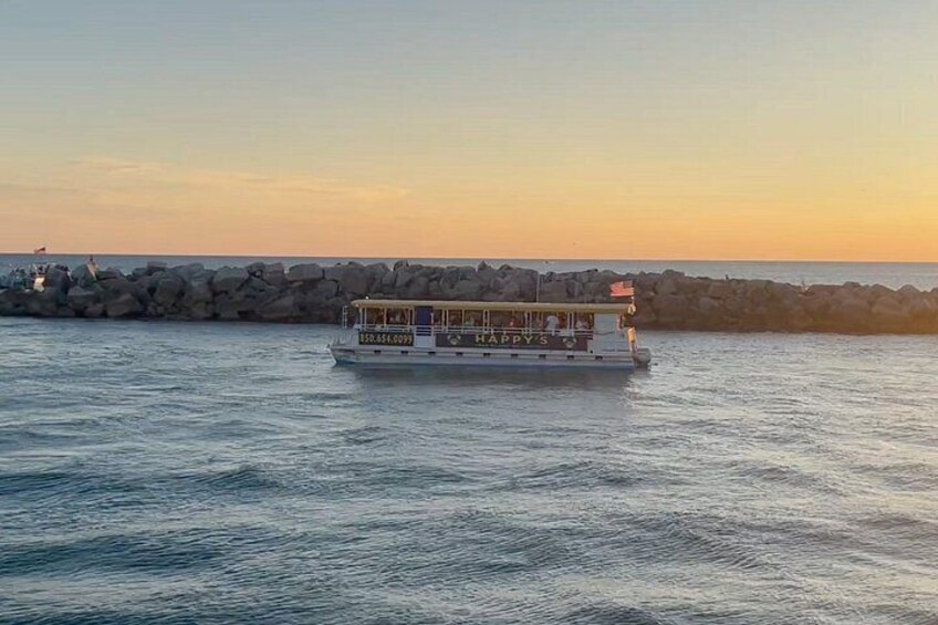 Un bote llamado 'HAPPY'S' en aguas tranquilas cerca de un rompeolas rocoso durante el atardecer. 2