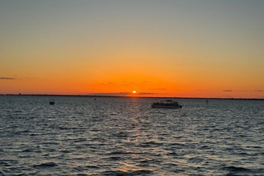 A sunset over a calm sea with a boat in the distance. 3