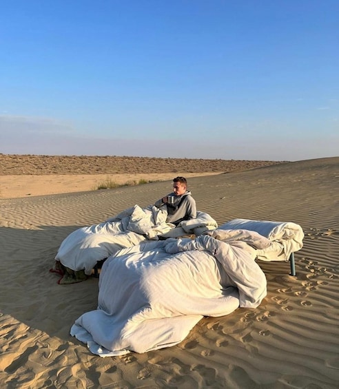 A person sitting on a sand dune with large white bags around them. 1