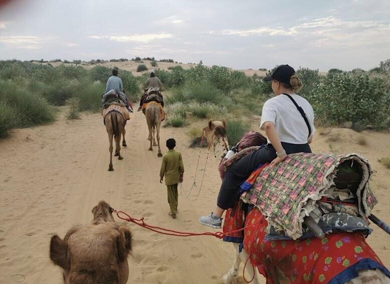 A group of people riding camels through a desert landscape. 3