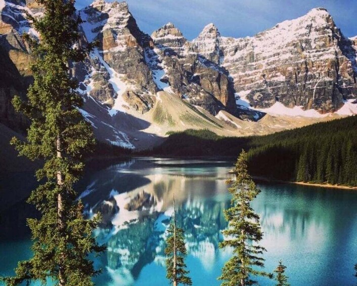 A mountain lake with reflections, surrounded by snow-capped peaks and coniferous trees. 1
