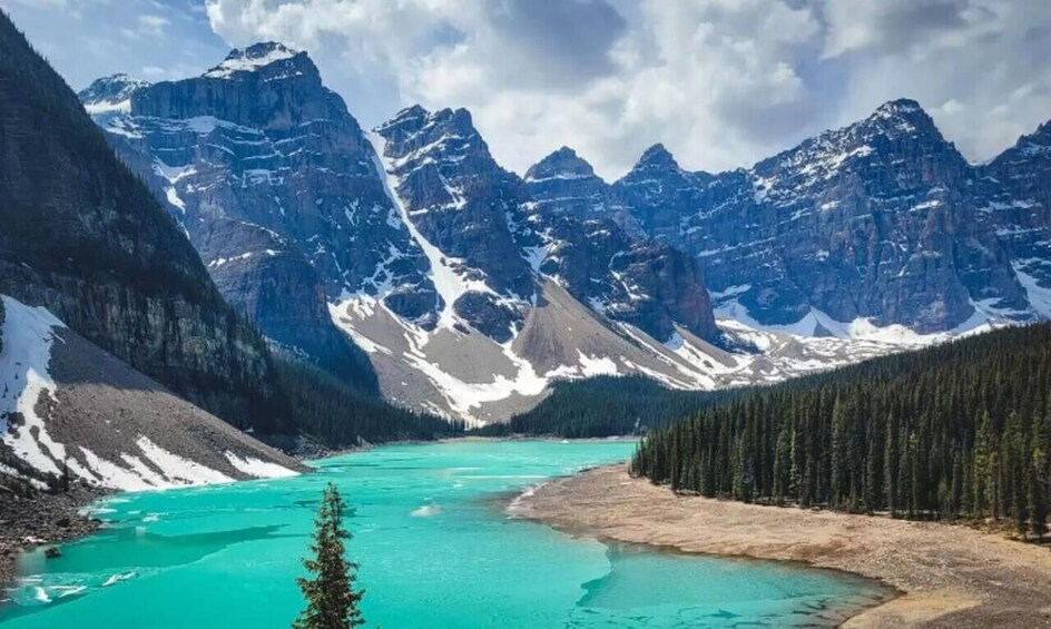 A turquoise lake surrounded by snow-capped mountains and dense forests. 5