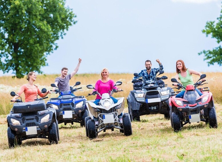 A group of people on all-terrain vehicles in a grassy field with trees in the background. 4