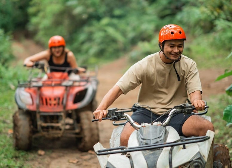 Two people riding ATVs on a dirt path in a forested area. 5