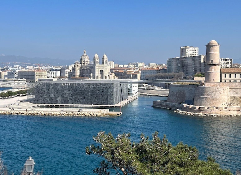 A coastal cityscape with a prominent cathedral, a modern building, and a historic tower. 5