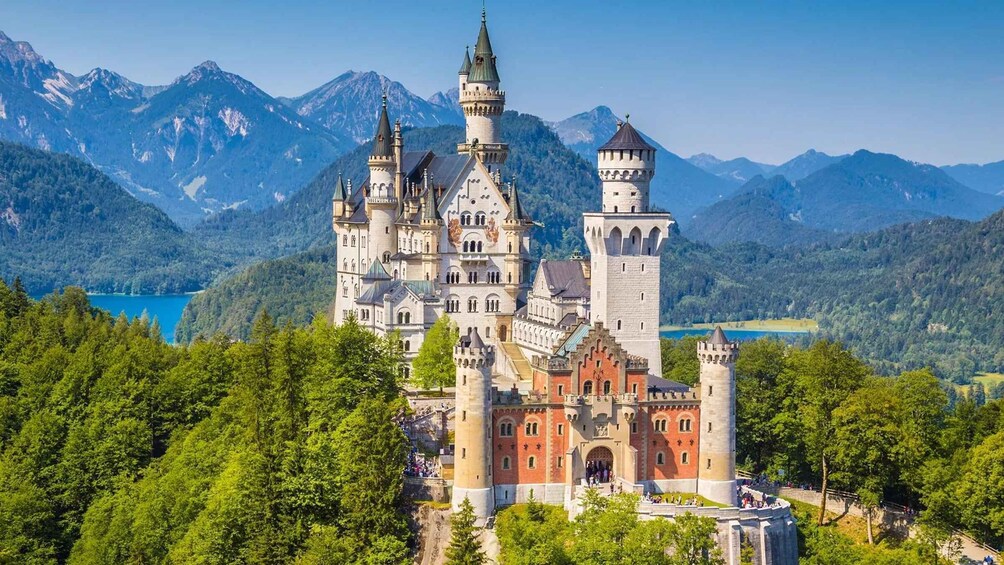A castle with multiple towers, surrounded by lush greenery and mountains. 1