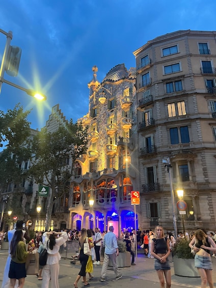 A historic building with ornate architecture and a crowd of people in a public square. 1