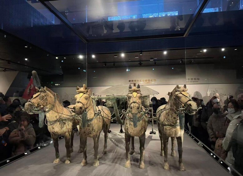 A museum exhibit with three ancient chariots on display. 5
