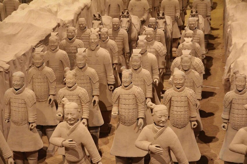 A collection of terracotta soldiers in uniform, lined up in rows, representing an ancient army. 1