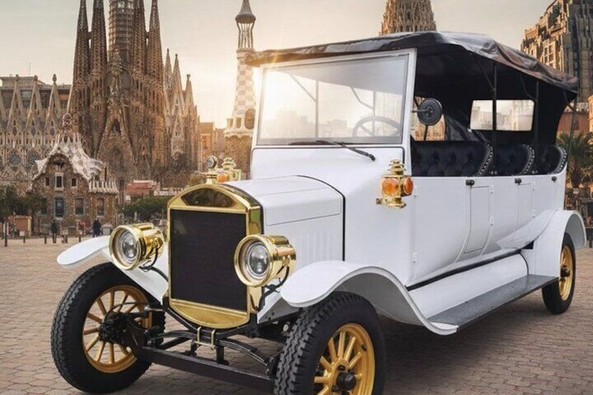 A vintage car with gold accents parked in front of a cathedral. 1