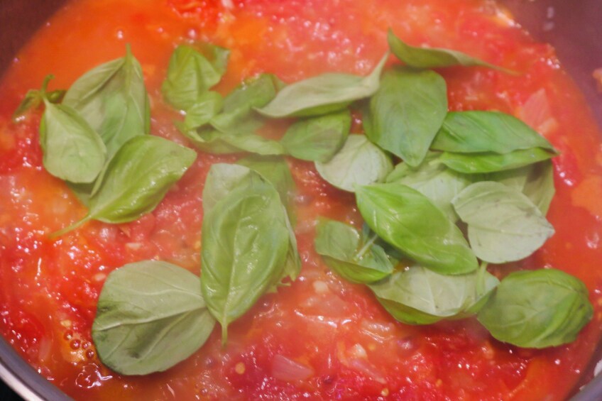 A pot of tomato sauce with basil leaves. 4