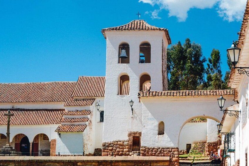 A white church with a bell tower, arched windows, and a tiled roof. 5