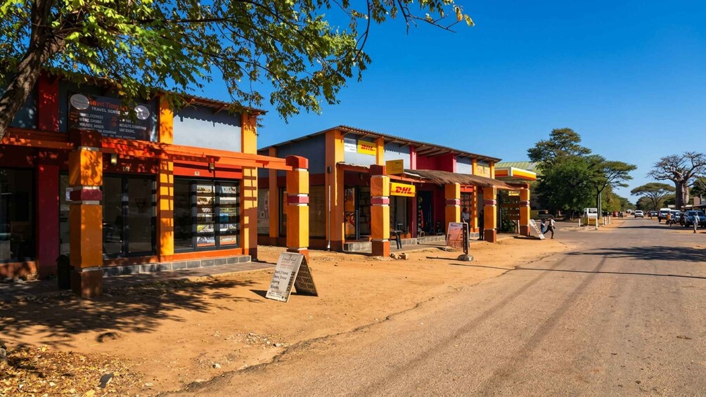 A roadside with colorful buildings, including a DHL store, and a clear blue sky. 4